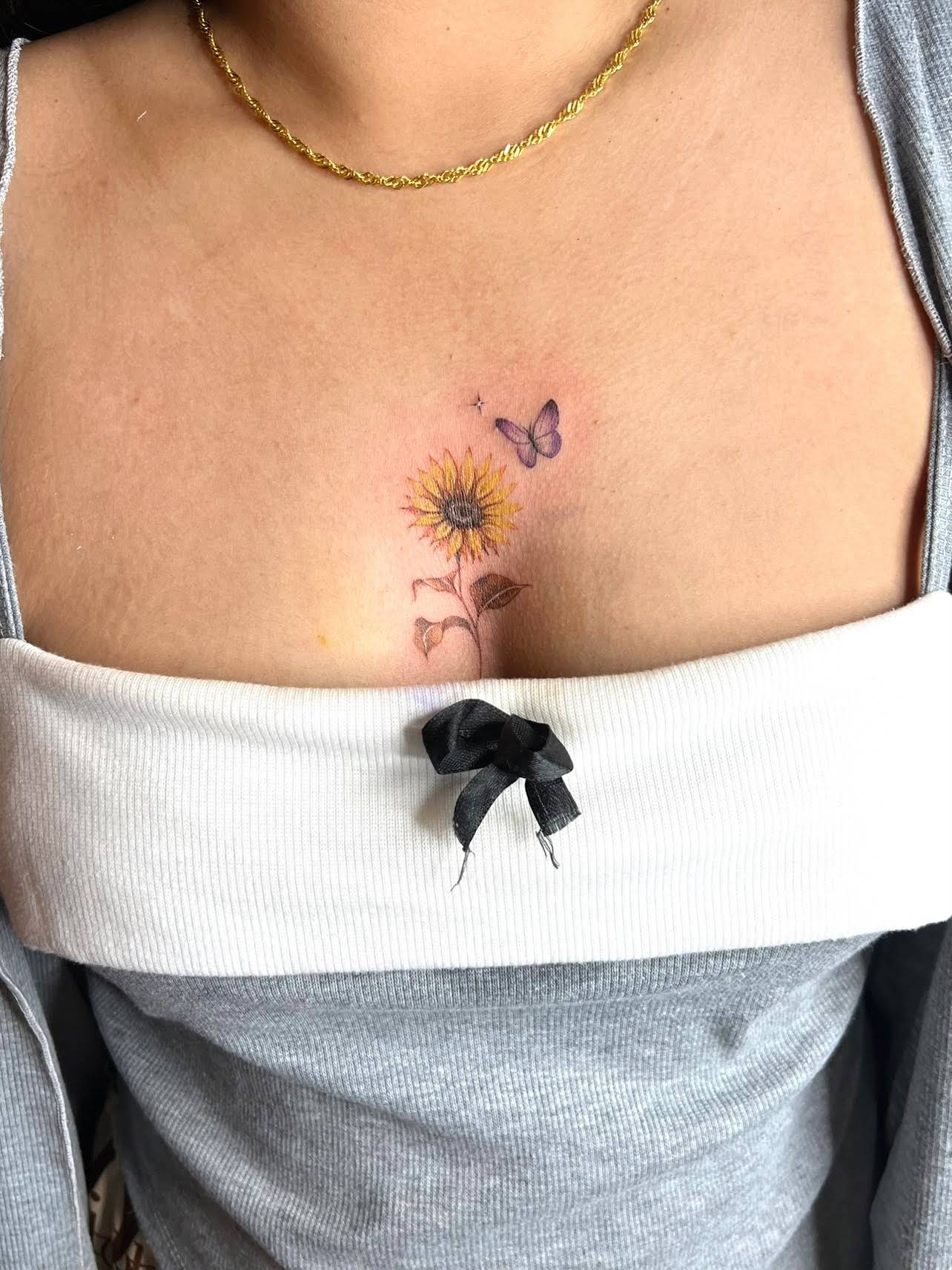 Delicate color sunflower with purple butterfly tattoo on chest